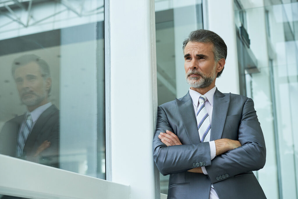 Pensive aged business executive looking through the window